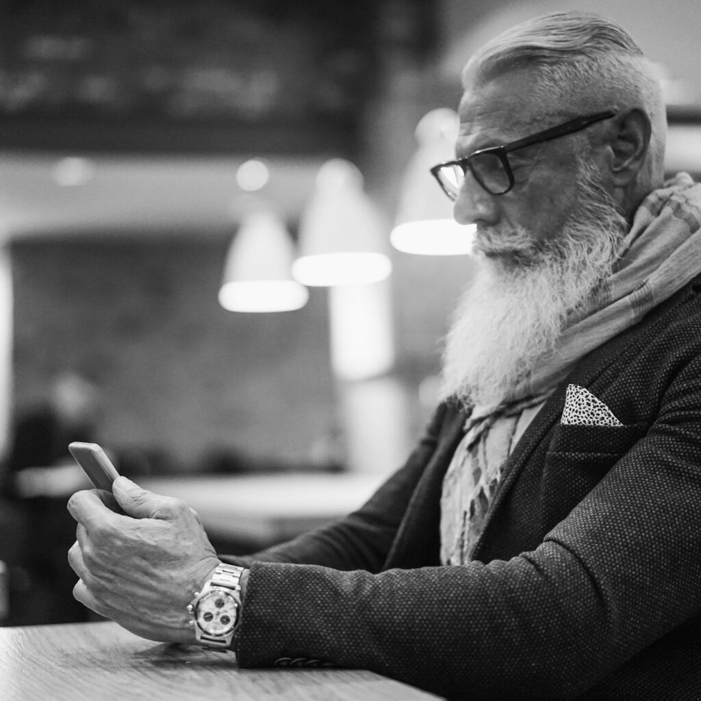 Happy trendy man using smartphone in bar cafeteria indoor - Fashion senior guy using internet app